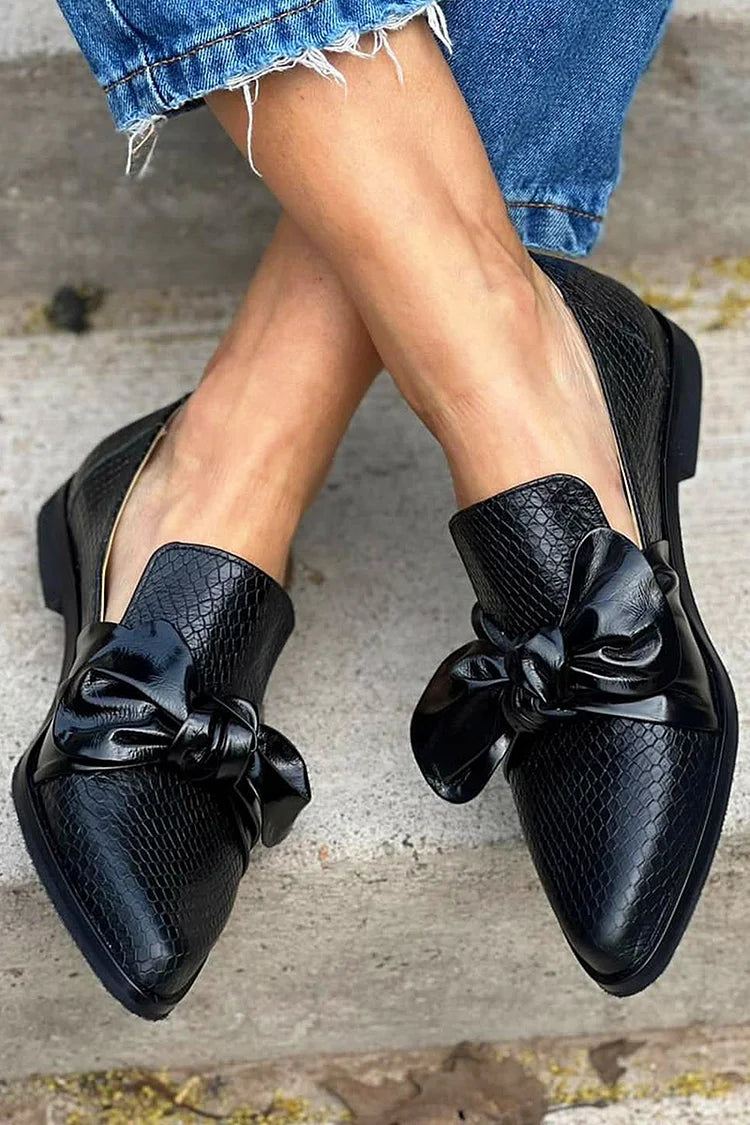 mocassins noirs slip-on à bout effilé, nœud et imprimé python.