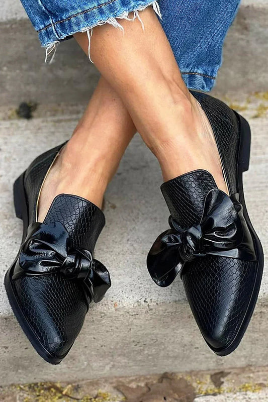 mocassins noirs slip-on à bout effilé, nœud et imprimé python.